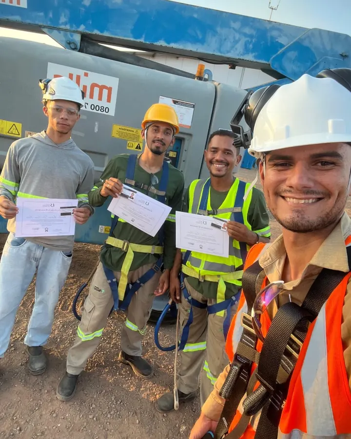 Turma sorridente com cintos de segurança e certificados após o treinamento de PEMT